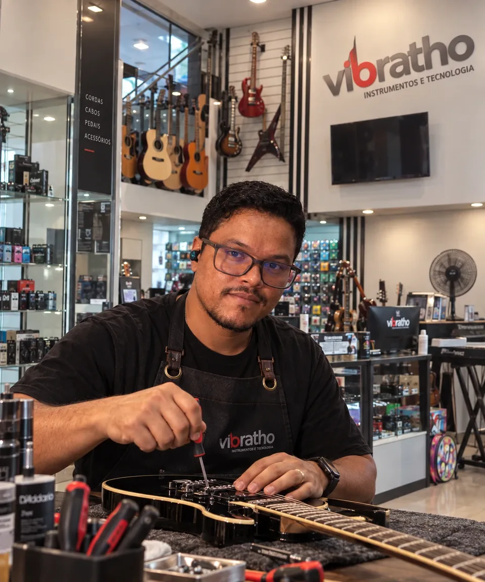 Luthier da Serviços Prime regulando uma guitarra na bancada da oficina em Brasília